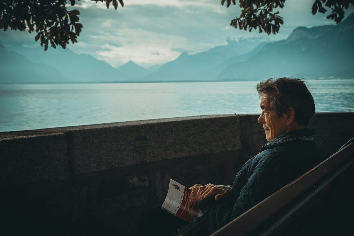 A reader sitting beside a peaceful mountain lake